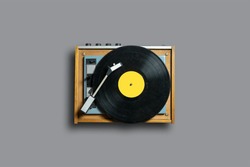 Vinyl record player with yellow label on a gray background. Modern phonograph record concept in trendy colors