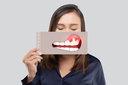 Asian woman in the dark blue shirt holding a paper with the broken tooth cartoon picture of his mouth against the gray background, Decayed tooth, The concept with healthcare gums and teeth