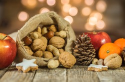 Rustic Christmas decoration, christmas sack with nuts, cookies, apples, oranges and pine cone decor.