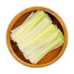 Leek strips, in a wooden bowl. Leeks julienne, leek leaves cut into strips. Allium ampeloprasum, a crunchy and firm vegetable with mild and onion-like taste. Close-up, from above, macro food photo.