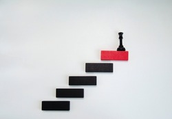 Black chess piece on red wooden block on white. Business planning, Risk Management, Solution, leader, strategy, Unique Concepts. Wood block stacking as step stair. Concept for business growth