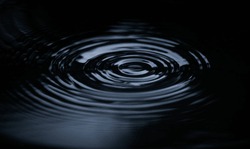 Ripple of water or water drop splash on black background. Abstract shape out of the water