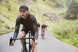 A young road cyclist dressed in black, winning race with friends in Cheddar Gorge, U.K