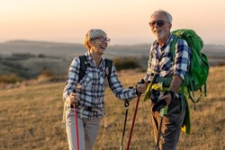 Old couple walking in nature and talk at sunset