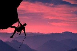 Side view on the young mountainer. Silhouette mountainer in action. The mountainer climbs to a hard route on the rock to reach its goal and success. Landscape of mountains and sunset in the background