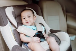 Cute baby boy smiling in safety car seat. Child transportation safety concept.