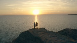 The man and woman standing on the rocky sea shore 