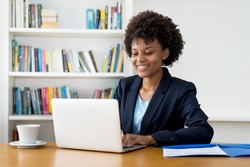Laughing african american business trainee working at computer indoors at home or at office
