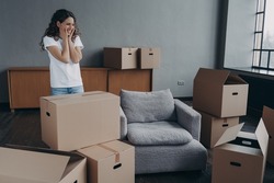 New first home, relocation. Happy hispanic female homeowner contemplating empty room, standing among cardboard boxes on moving day. Cute smiling woman renter feels happiness with removal.