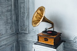 Music device. Old gramophone with plate or vinyl disk on wooden box. Antique brass record player. Gramophone with horn speaker. Retro entertainment concept.