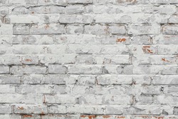 Non-linear pattern of an white shabby brick wall with natural patterns of paint chips. Restoration of semi-antique brick walls. A basic neutral background for a design project.