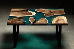 Expensive vintage furniture. The table is covered with epoxy resin and varnished. Luxury quality wood processing. Wooden table on a concrete background. A nautical epoxy river in a rectangular slab.