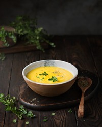 Vegetable puree soup on a dark wooden background. Pumpkin cream soup with thyme. Serving an autumn dish. Vegetarian food. Vegan cuisine. Dark style