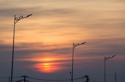 Silhouette of modern street lamps against the backdrop of the setting sun