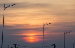 Silhouette of modern street lamps against the backdrop of the setting sun