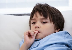 Portrait of little boy biting his finger nails while watching TV,Head shot kid with deep in thought, Childhood and family concept, Emotional Child portrait.