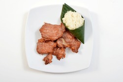 Fried beef with sticky rice served on white dish top view.
