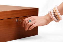 woman's hand wearing bracelets and opening a wooden jewlery box 