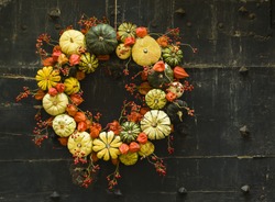 Handmade wreath of small pumpkins and zucchini on a vintage door