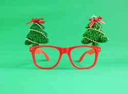 Christmas glasses decoration with Christmas tree and red ribbon on green background