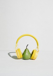 The music player in the shape of an pear with headphones. Fantasy on the theme of music and fruits, podcast for a healthy lifestyle