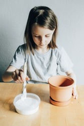 Girl paints a flower pot with white paint, hobby and decorative work
