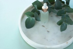 eucalyptus essential oil bottles, eucalyptus leaves  on marble plate on blue  backdrop. Beauty, wellness, body care concept. top view. copy space