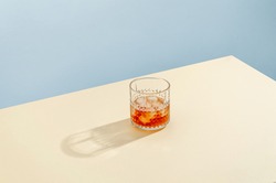 Glass with Whiskey and Ice Cube on Table on Blue Background. Modern Isometric Style. Creative Concept
