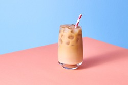 Iced Coffee with Milk in Tall Glasses on Pink Table and Blue Background. Isometric Horizontal Orientation