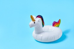 Inflatable white unicorn pool toy on blue background. Creative minimal concept.