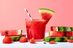 Close-up fresh watermelon juice or smoothie in glasses with watermelon pieces on pink background. Refreshing summer drink