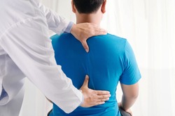Doctor physiotherapist doing healing treatment on man's back.Back pain patient, treatment, medical doctor, massage therapist.office syndrome
