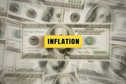  inflation text on a yellow wooden block placed on a dollar bill. The idea for FED considers interest rate hikes, world economics, and inflation control, Concept shows rising inflation.