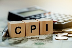CPI, consumer price index symbol. Wooden blocks with words CPI, consumer price index on dollar bills with a calculator, coins.  Business and CPI, Business and consumer price index concept.