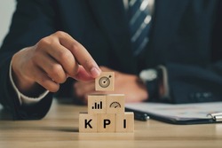 Key Performance Indicator (KPI). Businessmen arrange wood cubes with KPI icons. business goals, performance results, and indicators. For business planning and measuring success, target achievement.