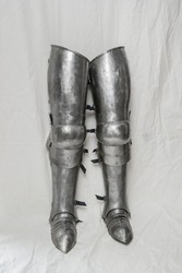 Steel set of armor for protecting legs from the 14th - 15th centuries. Part of knightly equipment, white background.