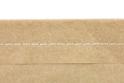 Sewing edge of brown paper on white background.
