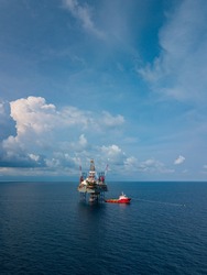 Aerial view from a drone of an offshore jack up rig at the offshore location with a supply boat