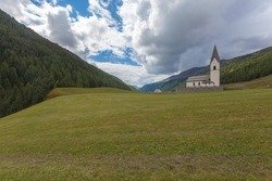 Isolated traditional church with cemetery in a South Tyrolean valley in the midst of perfectly manicured lawns, Vallelunga, Alto Adige, Italy