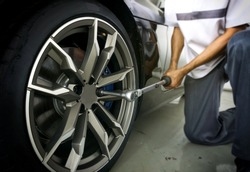 Auto mechanic using Torque wrench to inspection the wheel nuts for safety in travel in mechanics garage. Car repair center.