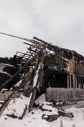 Photo of a burnt house in winter. Charred beams of a wooden house. Burned down house.