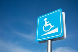 Disabled parking signage on the pole in blue and white colour with cloudy blue sky background.