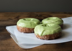 Low key shot of three cake donuts with matcha icing. 