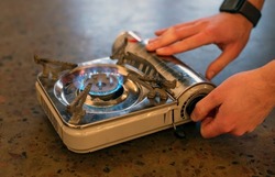 Active lifestyle. A man's hand turns on a portable gas stove. An alternative source for cooking at home during a power outage.