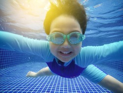 A boy is practicing swimming and diving in the blue pool.