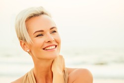 happy middle aged woman elegant looking and feeling confident on beach. spf useing concept. short haircut hairstyle