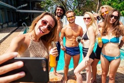 attractive six friends making self portrait on smartphone in swimmingpool