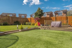 A newly completed and replanted landscaped garden with mixure of artificial and natural sown grass, borders planted, a new decking patio and garden ornaments surrounded by new erected wooden fencing. 