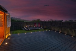 Ash grey composite decking built on two levels on a residential back garden with low voltage deck lights installed as well. Good Image for a landscape Gardiner