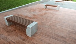 The bench is made of concrete and artificial wood, placed on a wood-patterned tile floor.